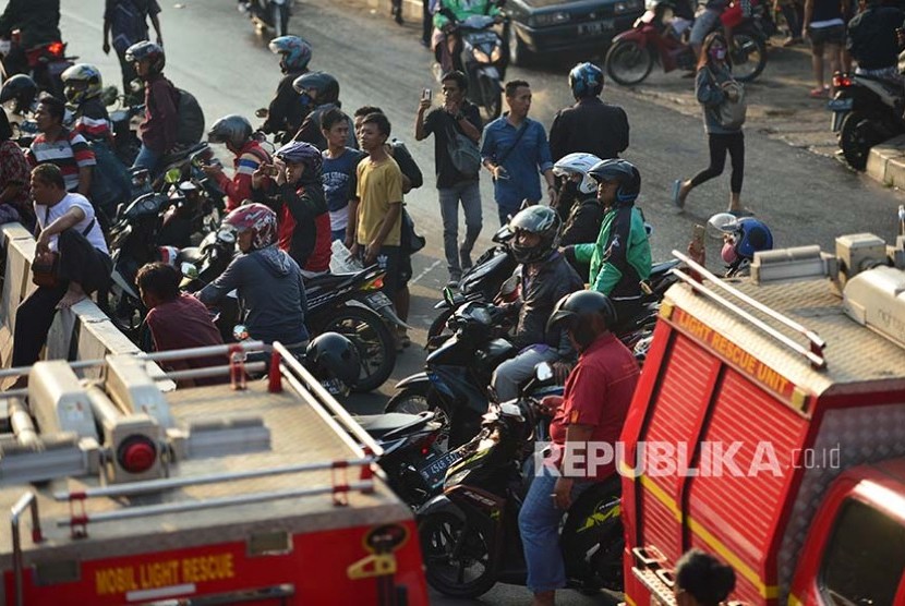 Pengedara sepeda motor yang melintas berhenti untuk melihat sejenak lokasi kebakaran Gedung Ramayana Pasar Minggu, Kamis (18/5)