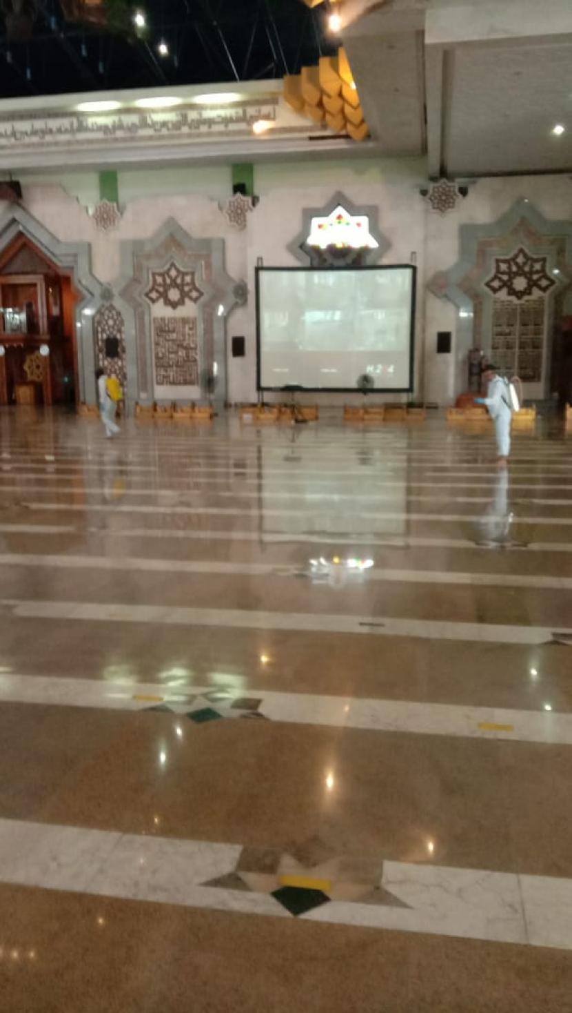 Pengelola membersihkan area masjid dengan cairan disinfektan. 