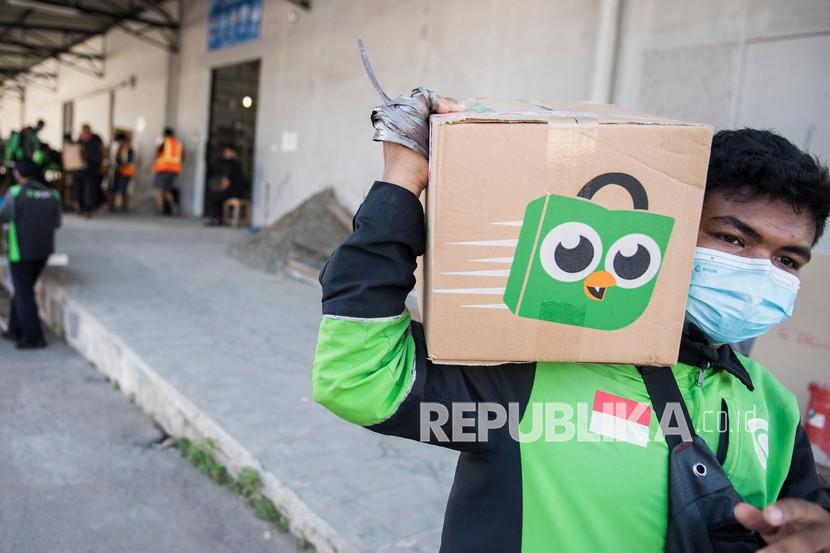 Pengemudi daring Gojek membawa kemasan paket dari Tokopedia di Titipaja Warehouse, Jakarta, Jumat (28/5/2021). 