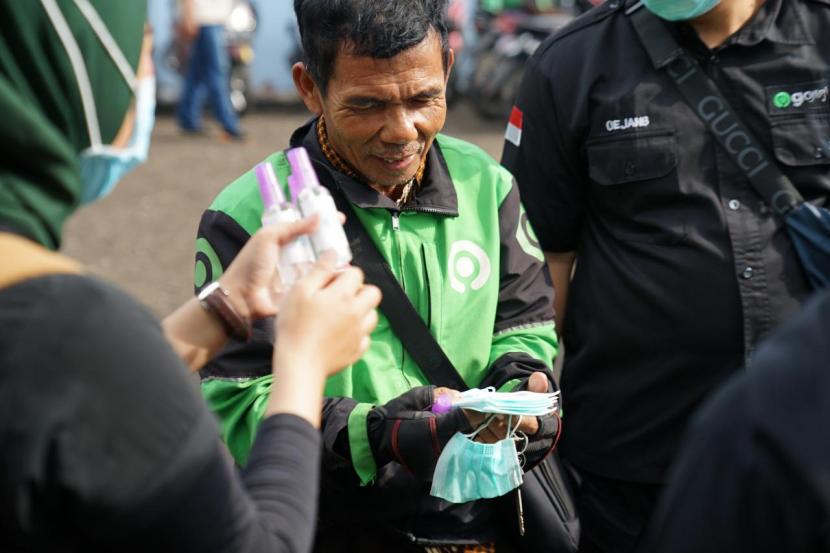 Pengemudi Gojek menerima hand sanitizer dan masker.