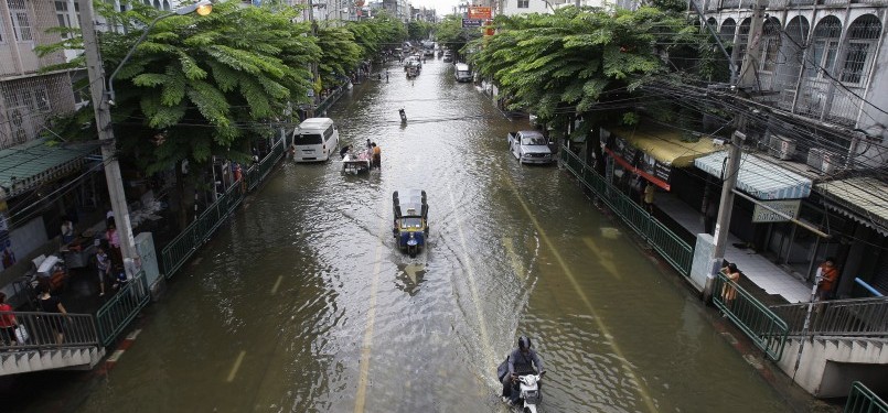 Pengemudi melintasi jalan yang terendam di Grand Palace di Bangkok, Thailand pada Jumat 28/10. (AP)