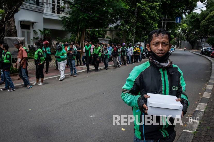 Pengemudi ojek daring menunjukkan nasi kotak yang didapatkannya di kawasan Menteng, Jakarta, Jumat (3/4/2020). Pembagian makanan gratis tersebut merupakan sebagai bentuk kepedulian terhadap sesama di tengah-tengah pandemi COVID-19. 