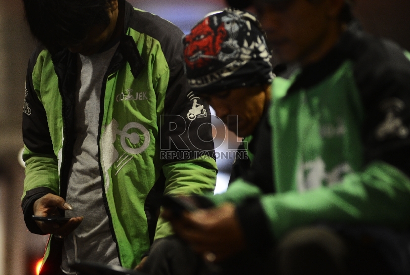  Pengemudi ojek online menunggu penumpang di Kawasan Jalan Sudirman, Jakarta Selatan, Jumat (18/12).
