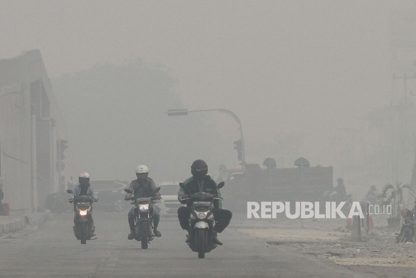 Pengendara kendaraan bermotor melintas di jalan Soekarno Hatta ketika kabut asap pekat dampak karhutla menyelimuti Kota Pekanbaru, Riau, Selasa (17/9/2019). 