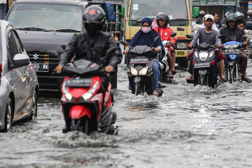 Pengendara kendaraan bermotor melintasi Jalan Raya Kutabumi yang tergenang banjir di Pasar Kemis, Kabupaten Tangerang, Banten, Senin (17/10/2022). Hujan deras serta buruknya sistem drainase di kawasan tersebut menyebabkan jalan raya tergenang banjir hingga 60 cm dan berimbas kepada kemacetan. 