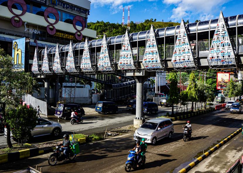 Pengendara melaju di bawah proyek jembatan penyeberangan orang (JPO) di Kota Jayapura, Provinsi Papua. Pemerintah pusat diminta intropeksi diri dan fokus terkait penanganan berbagai masalah di Papua. 