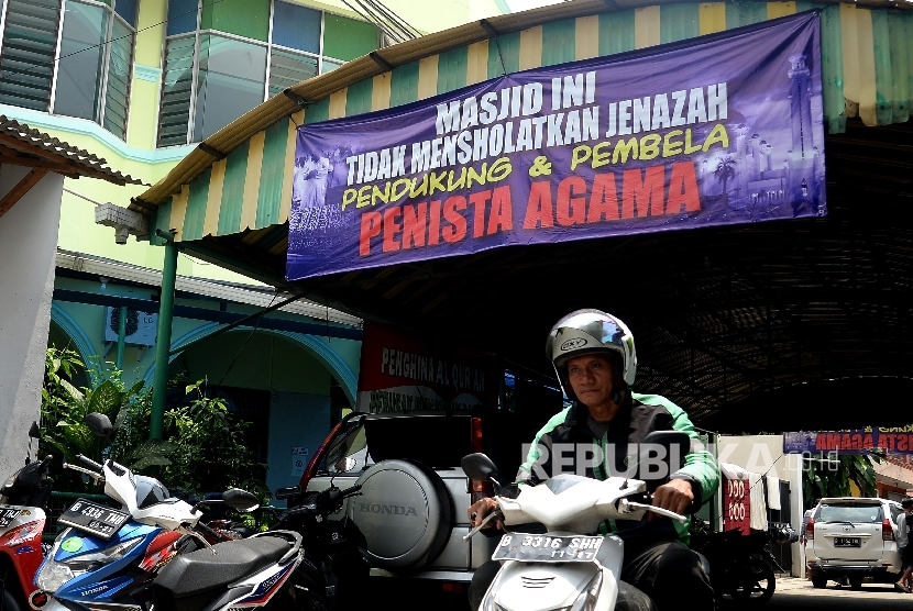 Pengendara melintas di bawah spanduk larangan mensholatkan jenazah pendukung dan pembela penista agama yang terpasang di Masjid Al-Jihad, Setiabudi, Jakarta, Ahad (26/2).
