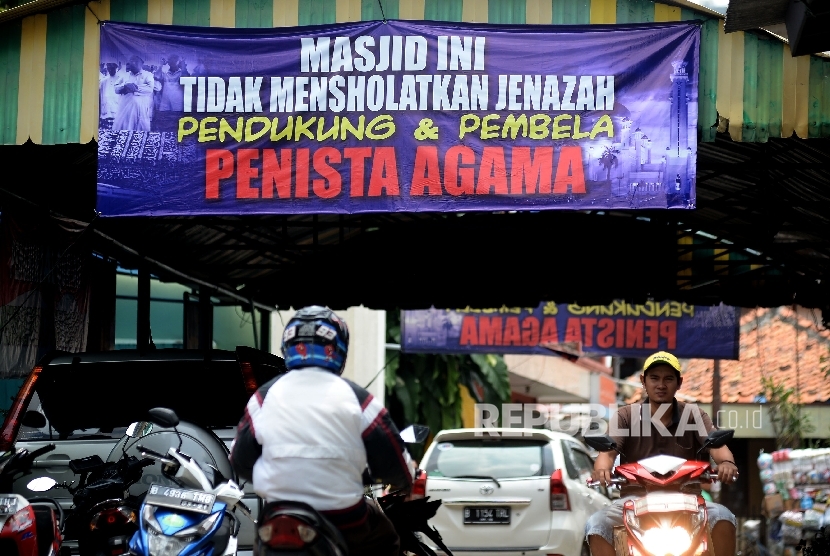 Pengendara melintas di bawah spanduk larangan mensholatkan jenazah pendukung dan pembela penista agama yang terpasang di Masjid Al-Jihad, Setiabudi, Jakarta, Ahad (26/2).