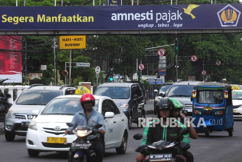  Pengendara melintas di dekat spanduk sosialisai pengampunan pajak yang terpasang di jembatan Penyebrangan orang (JPO) di kawasan Stasiun Gambir, Jakara, Ahad (31/7).  (Republika/ Agung Supriyanto)