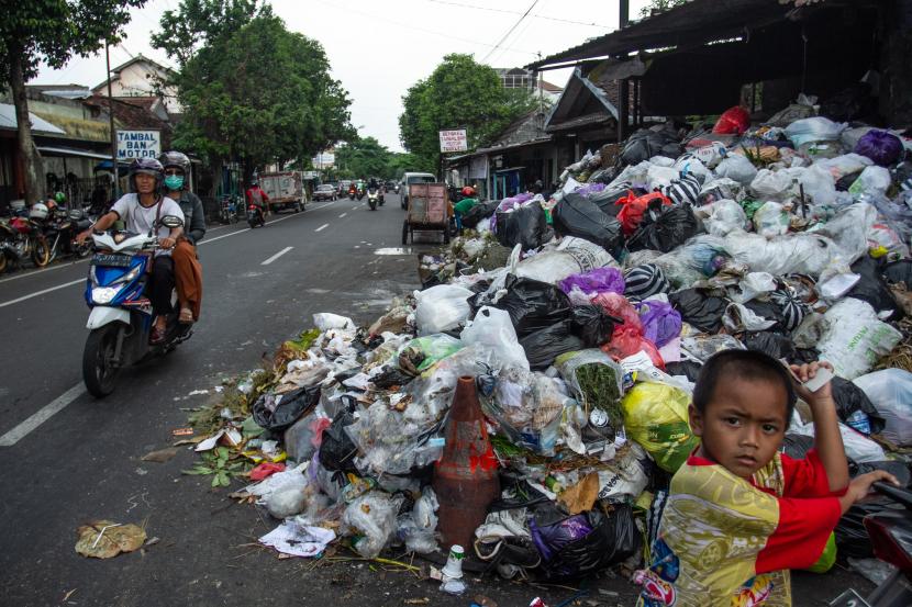 Pengendara melintas di dekat tumpukan sampah di kawasan Lempuyangan, Yogyakarta, Rabu (11/5/2022). Pemkot Yogyakarta menyemprot luberan sampah dengan disinfektar agar kurangi bau.