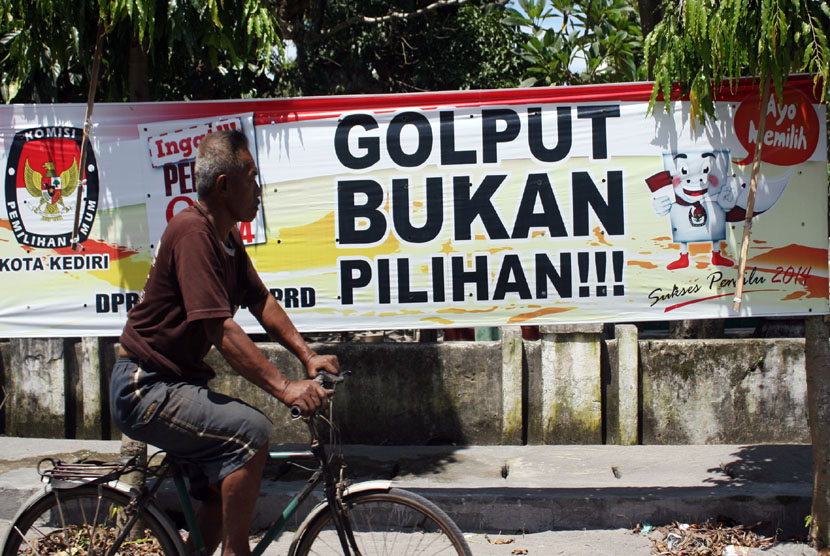 Pengendara melintas di depan atribut sosialisasi ajakan untuk tidak Golput yang dipasang di jalan raya kawasan Pesantren, Kota Kediri, Jawa Timur, Senin (7/4). 
