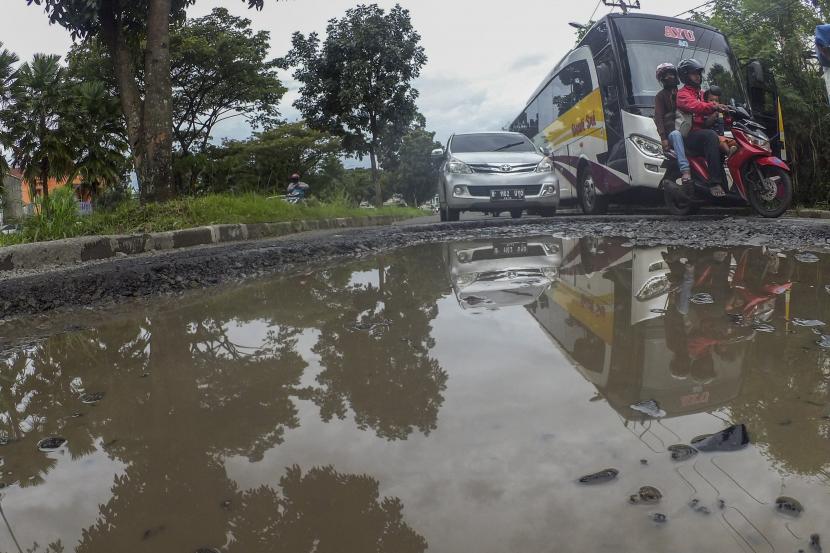 Pengendara melintas di jalan yang rusak di Jalan Raya Tegar Beriman, Cibinong, Kabupaten Bogor, Jawa Barat, Senin (8/3/2021). Salah satu akses jalan menuju kawasan Pemerintahan Kabupaten Bogor serta akses menuju Stasiun Bojonggede tersebut rusak dan berlubang sehingga membahayakan bagi pengendara yang melintas.