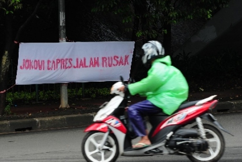 Pengendara melintas didepan spanduk kampanye hitam capres di jalan Dewi Sartika, Jakarta, Rabu (29/1). Meski belum resmi menjadi Capres, Gurbernur Joko Widodo telah mendapat serangan kampanye hitam dalam bentuk spanduk kritikan.
