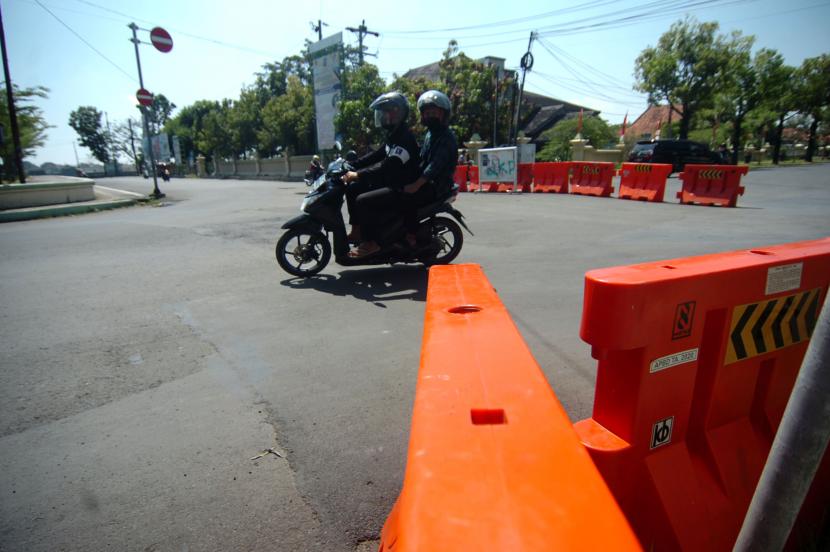 Pengendara melintas samping pembatas jalan (water barier) yang dibuka di Alun-alun Kabupaten Tegal, Jawa Tengah, Senin (26/7/2021). Pada akhir pekan lalu sempat beredar ajakan aksi menolak perpanjangan PPKM di media sosial. (ilustrasi)