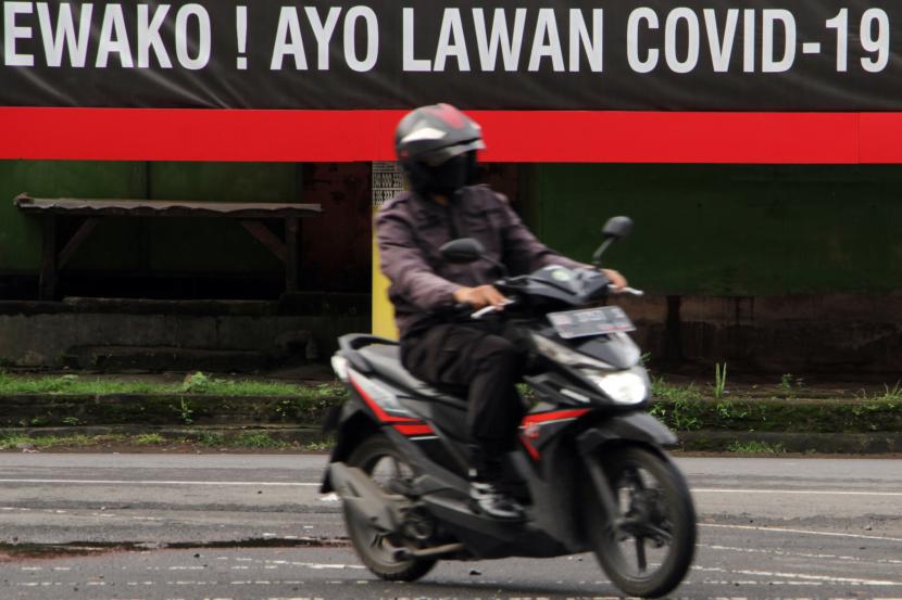 Pengendara melintasi baliho sosialisasi melawan COVID-19 di Makassar, Sulawesi Selatan, Jumat (11/2/2022). Status Darurat Covid-19 Usai, Kemenkes Siapkan Pedoman Tata Kelola Covid-19