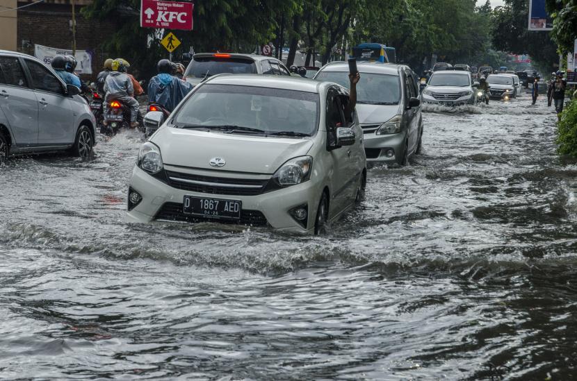 Pengendara melintasi banjir di jalan Jakarta, Bandung, Jawa Barat, Jumat (26/11/2021). Kawasan tesebut kerap dilanda banjir saat intensitas hujan yang tinggi akibat drainase yang buruk sehingga menganggu arus lalu lintas. 