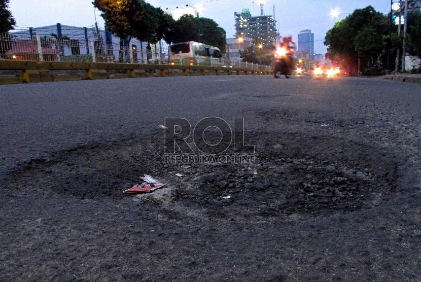 Pengendara melintasi jalan berlubang di kawasan Mampang Prapatan, Jakarta Selatan, Rabu (11/2).