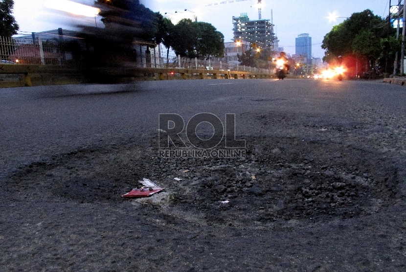 Pengendara melintasi jalan berlubang di kawasan Mampang Prapatan, Jakarta Selatan, Rabu (11/2).