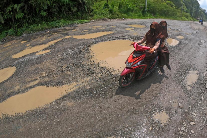 Pengendara melintasi Jalan Lintas Sumatera yang rusak di Sungai Lansek, Sijunjung, Sumatera Barat, Kamis (18/3). Jalan penghubung Sumatera Barat dengan Jambi itu rusak dan berlubang di sejumlah titik sehingga membahayakan pengendara.