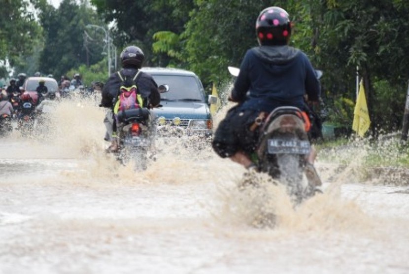 Pengendara melintasi jalan yang terendam banjir di Sendangrejo, Madiun, Jawa Timur, Selasa (5/3/2019). Luapan sejumlah anak sungai Madiun yang disebabkan hujan deras mengakibatkan beberapa wilayah di daerah itu terendam. 