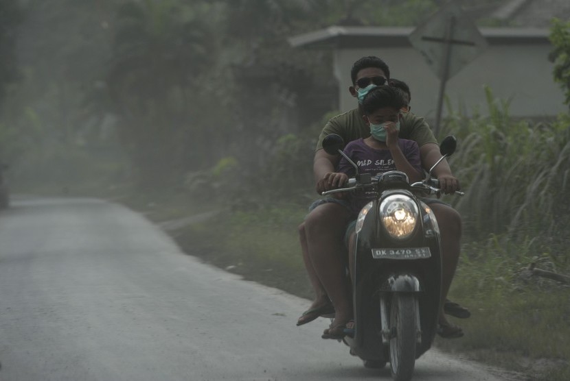 Pengendara melintasi jalan yang tertutup abu vulkanik Gunung Agung di Desa Jungutan yaitu desa yang termasuk dalam kawasan rawan bencana, Karangasem, Bali, Senin (27/11). 
