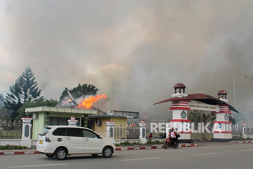 Pengendara melintasi Kantor Bupati Jayawijaya yang terbakar saat aksi unjuk rasa di Wamena, Jayawijaya, Papua, Senin (23/9/2019). 