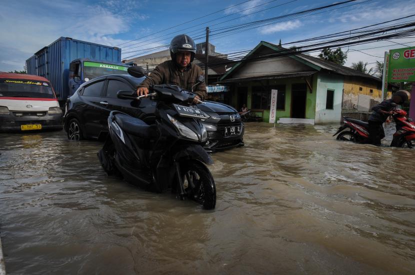 Pengendara mendorong motornya melintasi banjir di Pandeglang, Banten, Selasa (1/3/2022). Hujan deras yang terjadi di daerah tersebut mengakibatkan sejumlah kawasan di Pandeglang terendam banjir.
