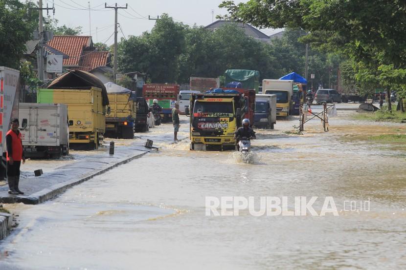Pengendara menerobos banjir yang menggenang di jalur Pantura Kandanghaur, Indramayu, Jawa Barat, Selasa (9/2/2021). Banjir setinggi 40 cm merendam jalur Pantura Kandanghaur sejak Senin (8/2) itu menyebabkan antrean kendaraan yang cukup panjang.