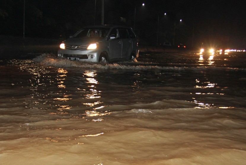 Pengendara menerobos banjir di jalan tol. 