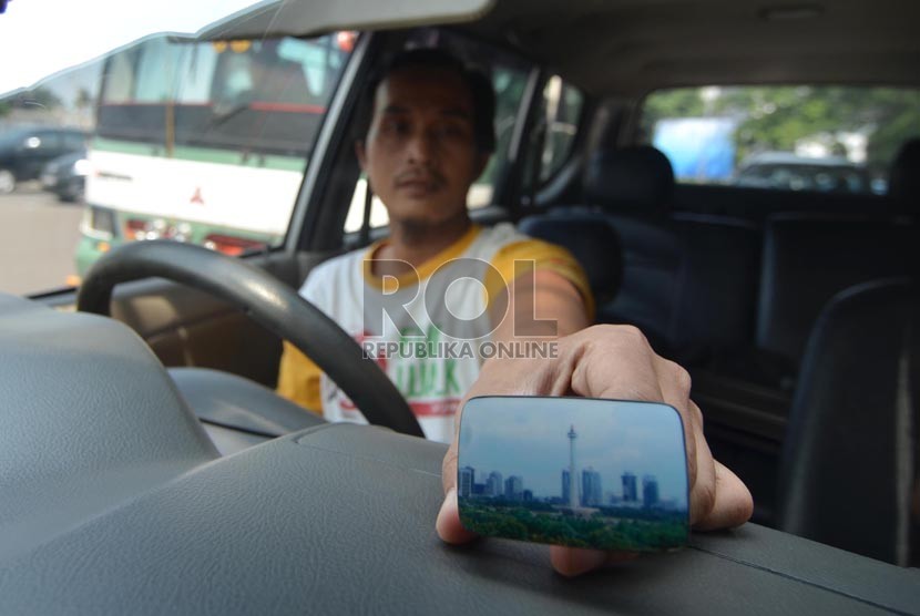 Pengendara menujukkan contoh alat On Board Unit (OBU) untuk program Electronic Road Pricing (ERP) di Jalan Jendral Sudirman, Jakarta Pusat, Selasa (15/7).  (Republika/Rakhmawaty La'lang)