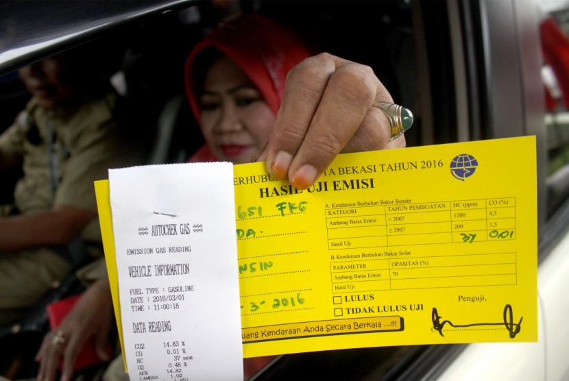 Pengendara menunjukan kartu hasil uji emisi usai melakukan uji emisi kendaraannya di halaman Kantor Pemerintah Kota Bekasi, Jawa Barat.