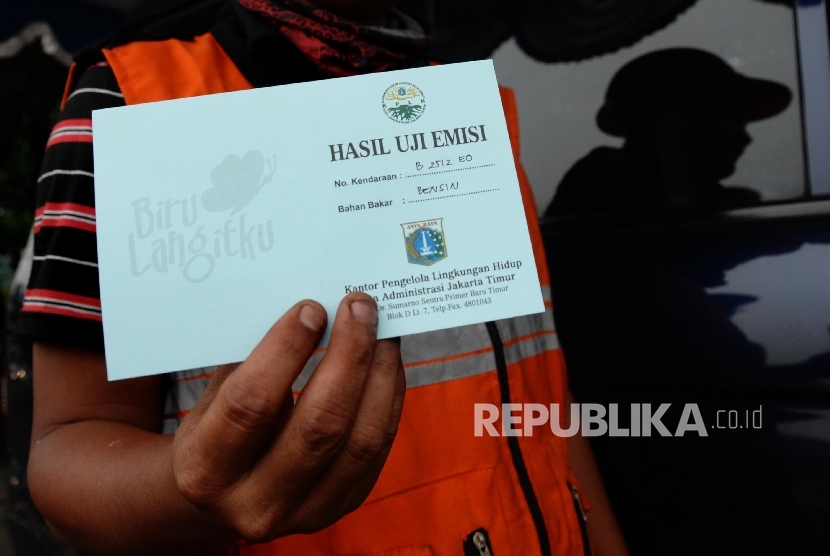 Pengendara menunjukan kartu hasil uji emisi usai melakukan uji emisi gas buang pada kendaraan roda empat yang melintas di Jalan Pemuda, Jakarta Timur, Selasa (26/4). (Republika / Yasin Habibi)