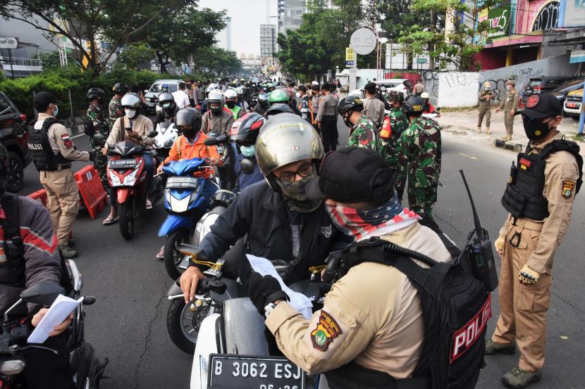 Pengendara menunjukkan Surat Tanda Registrasi Pekerja (STRP) kepada petugas di pos penyekatan pembatasan mobilitas masyarakat pada PPKM Darurat di wilayah perbatasan menuju Jakarta di Jalan Margonda, Depok, Jawa Barat.