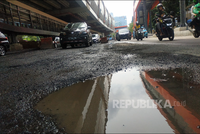 Pengendara mobil dan sepeda motor bermanuver menghindari badan jalan rusak di Jl HR Rasuna Said Jakarta, Rabu (4/1/2023). Genangan air cukup dalam, jalan bergelombang, hingga batu kerikil mengadang pengendara di jalanan. 