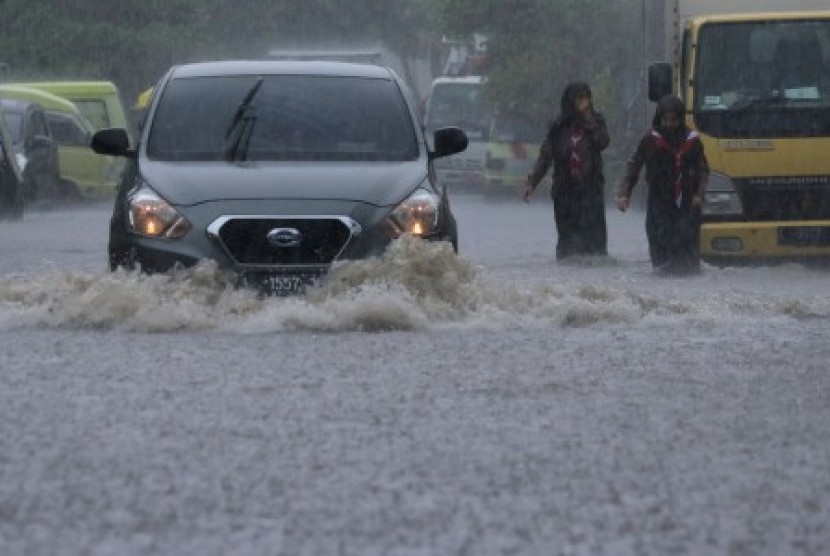 Pengendara mobil menerjang air yang menggenangi Jalan Krembangan Makam, Surabaya, Jawa Timur, Jumat (24/11). Hujan deras menyebabkan beberapa area di Surabaya tergenang air. 