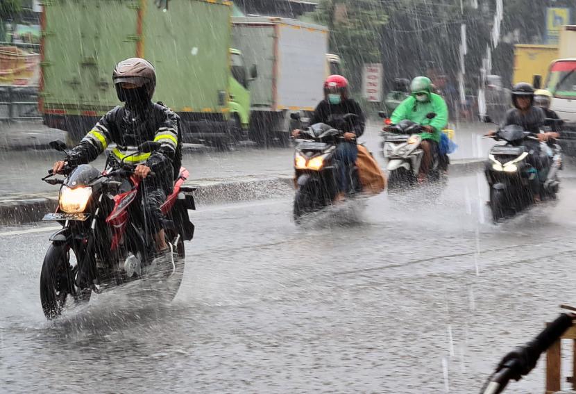 Pengendara motor berkendara di tengah hujan deras (ilustrasi)