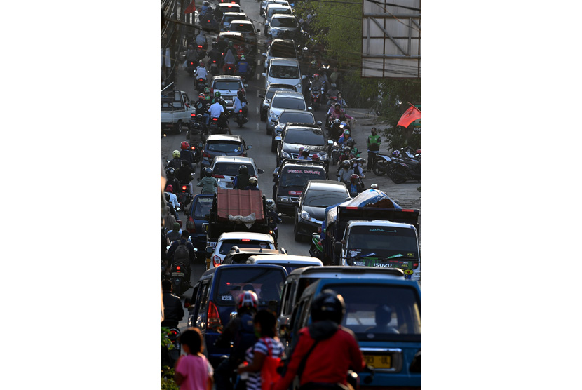 Pengendara motor dan mobil antre melintas saat terjadi keramaian lalu lintas di Jalan Raya Sawangan, Depok.