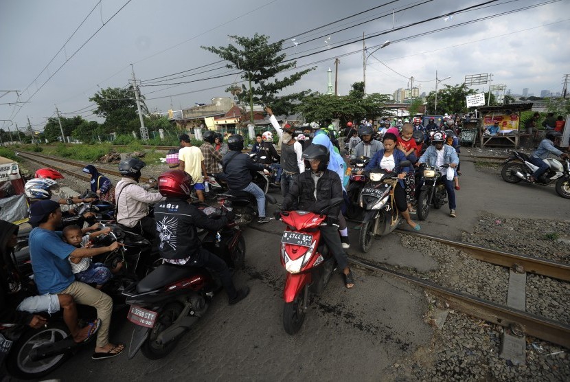 Pengendara motor melewati perlintasan kereta api tanpa palang pintu di kawasan Tambora, Jakarta Barat, Jumat (15/4). (Antara/Sigid Kurniawan)