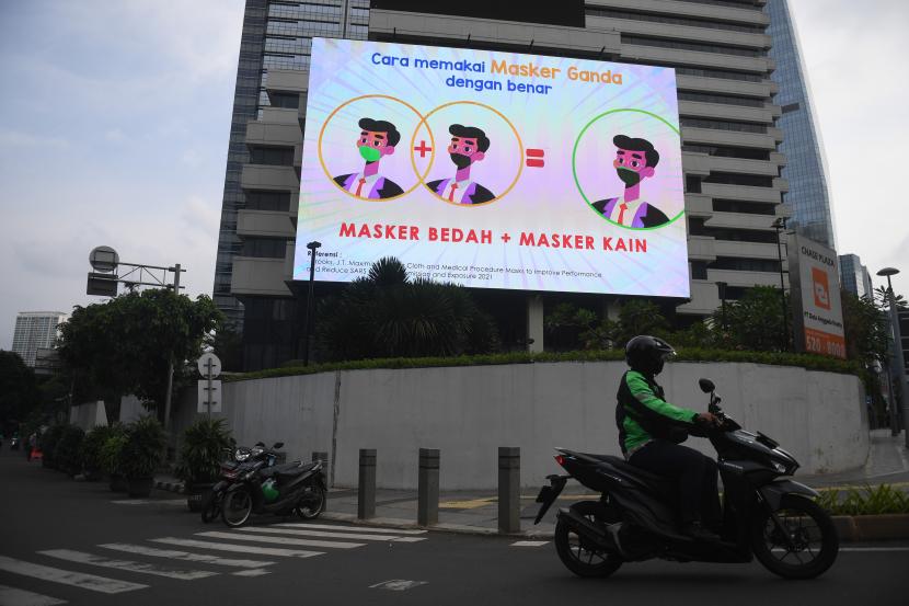 Pengendara motor melintas di dekat layar digital yang menampilkan imbauan protokol kesehatan di Jakarta, Senin (17/1/2022). Pemerintah resmi memperpanjang masa Pemberlakuan Pembatasan Kegiatan Masyarakat (PPKM) Jawa-Bali hingga 24 Januari 2022. Epidemiolog Minta Status PPKM Dinaikkan