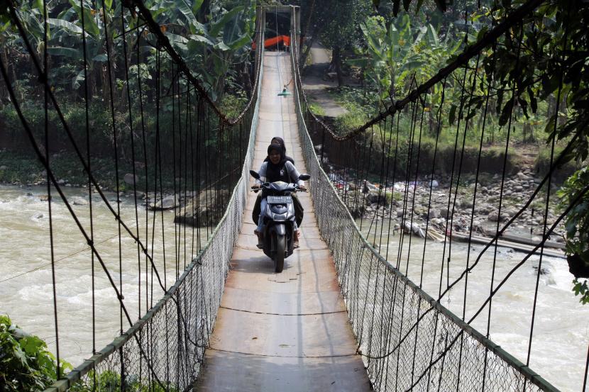 Pengendara motor melintas di jembatan gantung Kantalarang di atas Sungai Cikaniki, Kabupaten Bogor, Jawa Barat, Rabu (9/6/2021). 