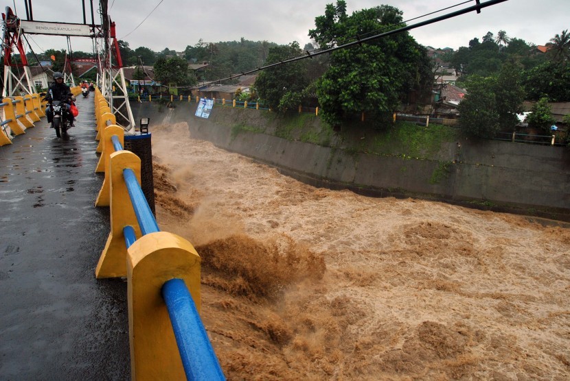 Pengendara motor melintas diatas jembatan saat tinggi muka air sungai Ciliwung naik di Bendung Katulampa, Kota Bogor, Jawa Barat, Rabu (1/1/2020). Hujan dengan intensitas tinggi yang mengguyur wilayah Bogor dan sekitarnya sejak Selasa (31/12/2019) malam tersebut menyebabkan tinggi muka air di Bendung Katulampa, Bogor naik menyentuh 170 cm dengan status siaga dua.