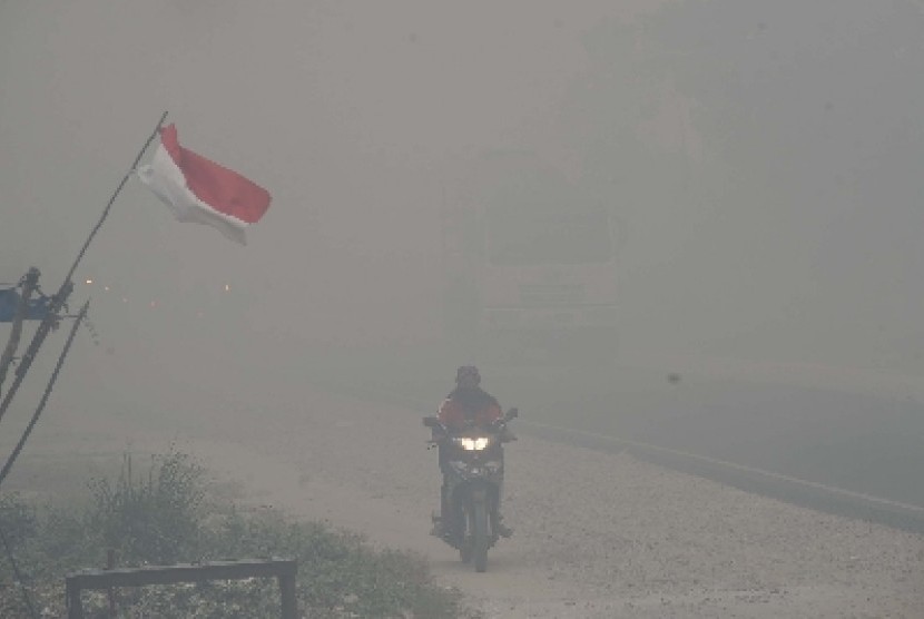 Pengendara motor melintas menembus kabut asap di kawasan Rimbo Panjang, Tambang, Kampar, Riau, Selasa (1/9).