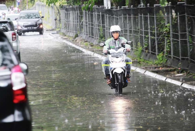 Pengendara motor melintas saat hujan.