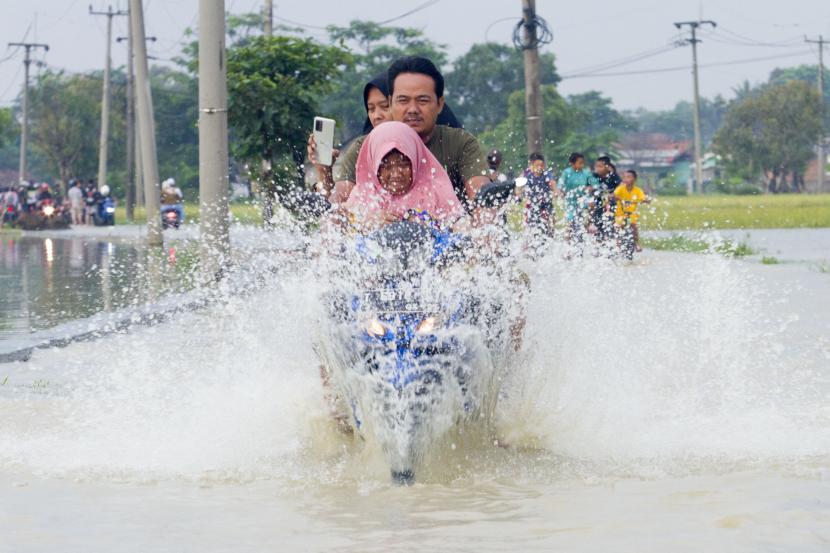 Pengendara motor melintasi banjir di Desa Karangligar, Karawang, Jawa Barat, Ahad (12/12/2021). Badan Penanggulangan Bencana Daerah (BPBD) Karawang mencatat sebanyak 236 rumah dan 829 jiwa terdampak banjir di wilayah itu yang disebabkan meluapnya air sungai Citarum.