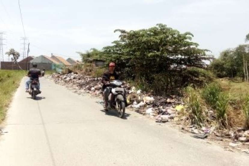Pengendara motor melintasi jalan di tepi Sungai Cisangkuy, Jalan Rancatungku, Pameungpeuk  yang tepiannya dipenuhi sampah, Selasa (25/9). 