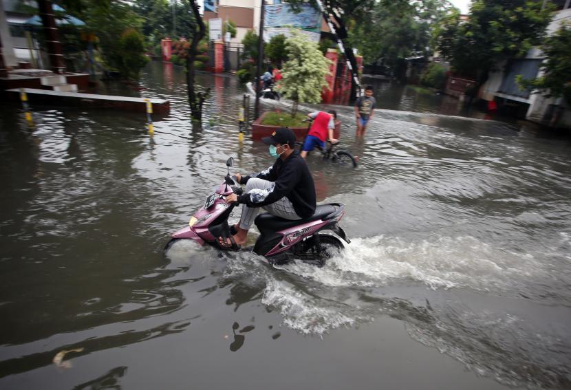 Pengendara motor melintasi jalanan yang terendam banjir di Perumahan Taman Asri, Tangerang, Banten, Selasa (21/12/2021). Banjir setinggi lutut orang dewasa tersebut disebabkan intensitas hujan yang tinggi di Kota Tangerang dan sekitarnya. 