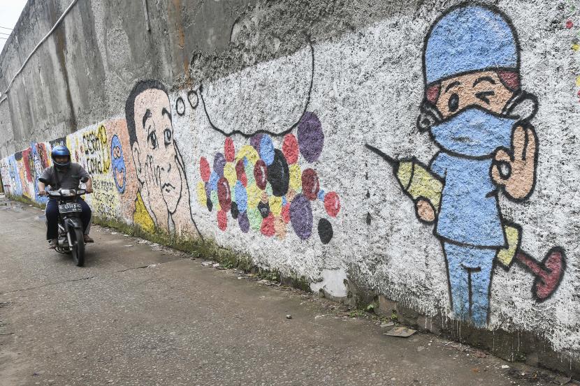 Pengendara motor melintasi mural bertemakan sosialisasi untuk vaksinasi Covid-19 di Bekasi, Jawa Barat, Senin (15/11/2021). Kasus Covid-19 di Indonesia melandai sebulan terakhir. Pola transmisi Covid-19 di Indonesia disebut mirip dengan India.