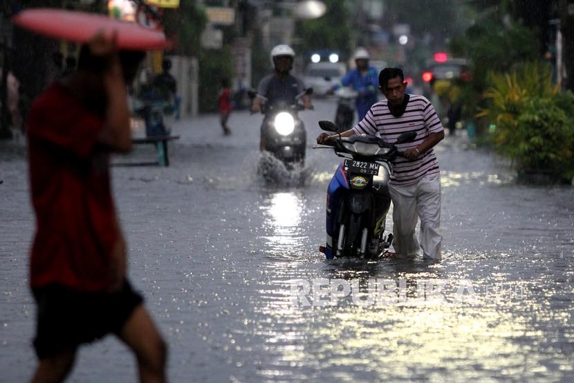 Pengendara motor mendorong motornya yang mogok akibat genangan air di Jalan Penjaringan Timur, Surabaya, Jawa Timur, Sabtu (5/12/2020). Hujan deras yang berlangsung sekitar empat jam itu menyebabkan sejumlah pohon tumbang dan beberapa kawasan di Surabaya tergenang banjir. 