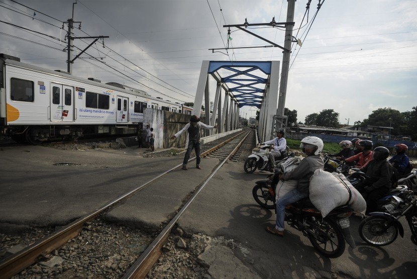 Pengendara motor menunggu KRL lewat di perlintasan kereta api tanpa palang pintu, kawasan Tambora, Jakarta Barat, Jumat (15/4). (Antara/Sigid Kurniawan)