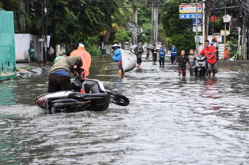 Pengendara motor terjatuh saat melintasi genangan air di kawasan Perumahan Green Garden, Kedoya, Jakarta Barat, Ahad (7/2/2021).